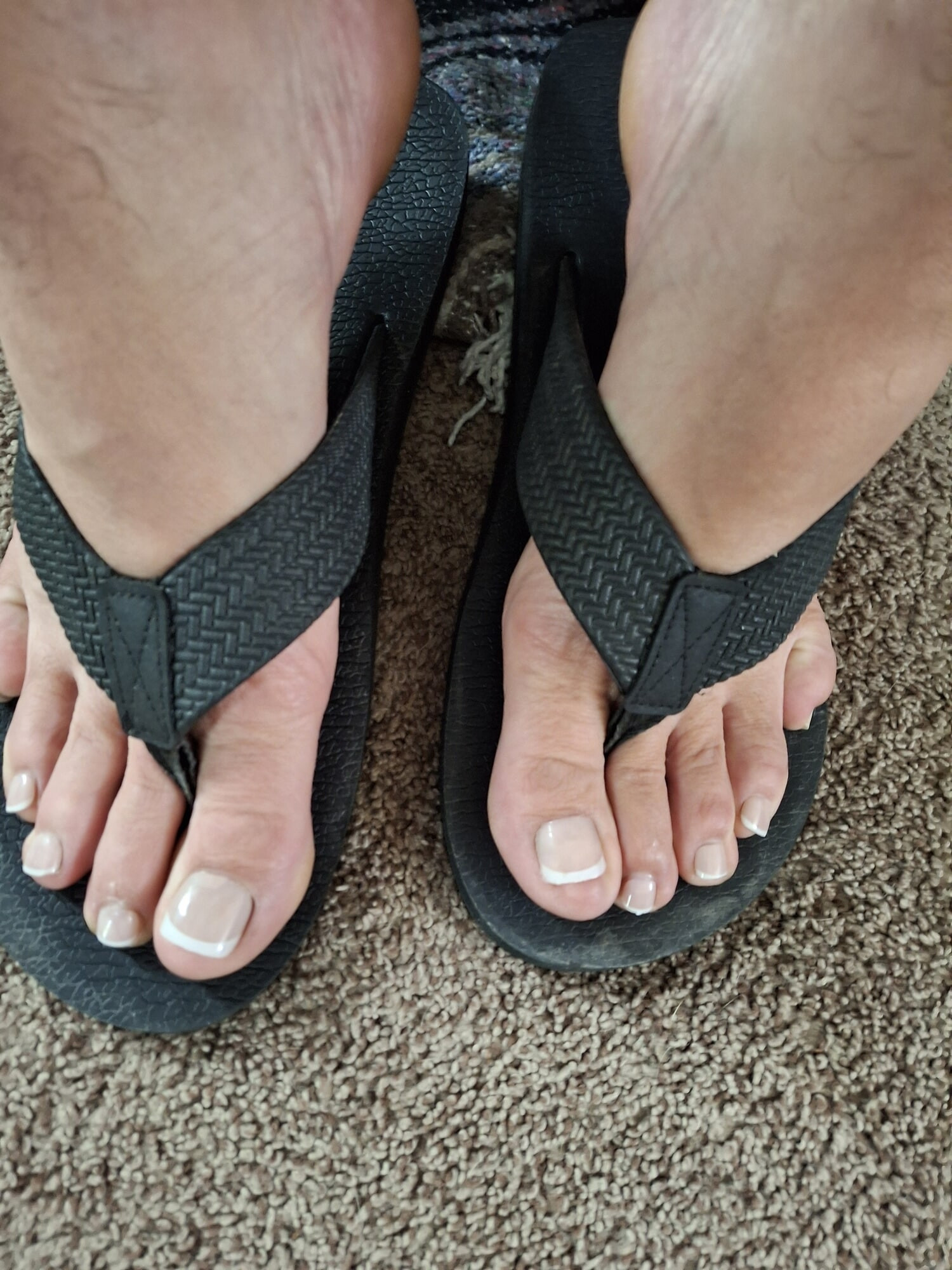 My feet in flip flops with a French pedicure