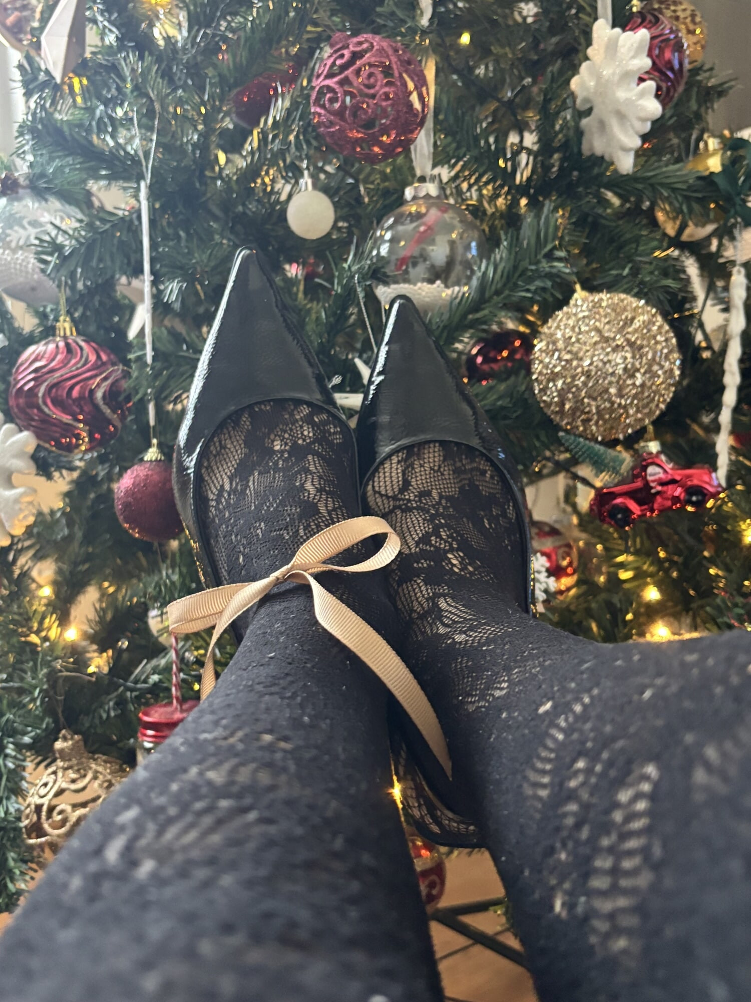 Feet in heels and stockings under a christmas three