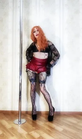 a bright red haired girl in lace stockings and a cape makes         