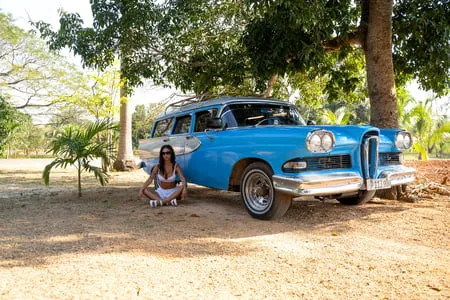 monika fox in white next to a vintage car in cuba         