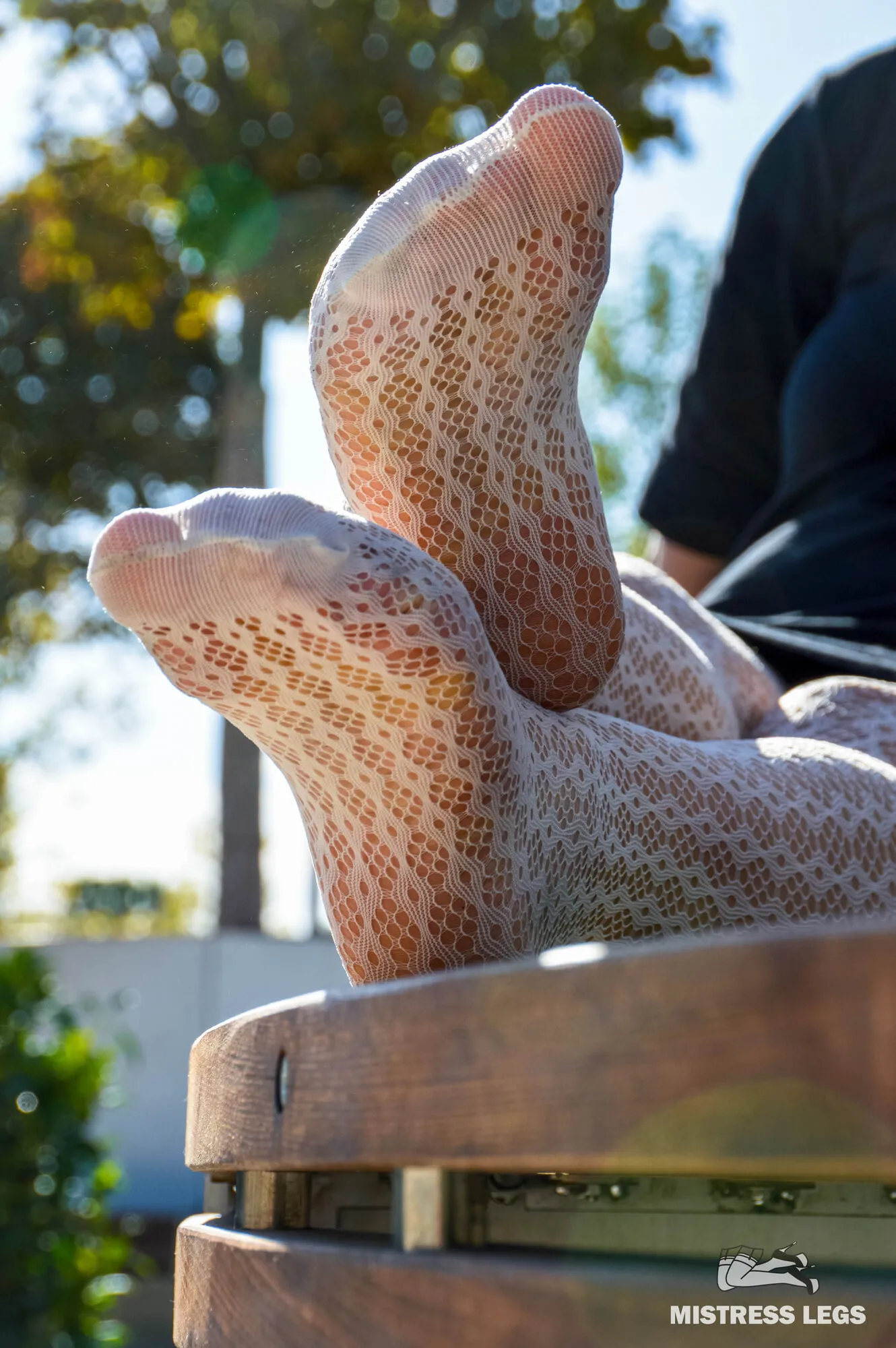 Sexy legs in white fishnet tights in the park