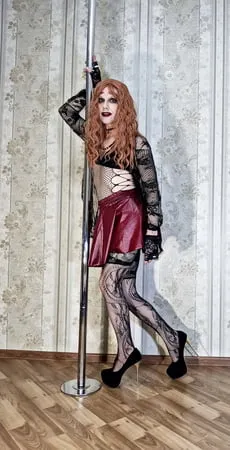 a bright red haired girl in lace stockings and a cape makes         