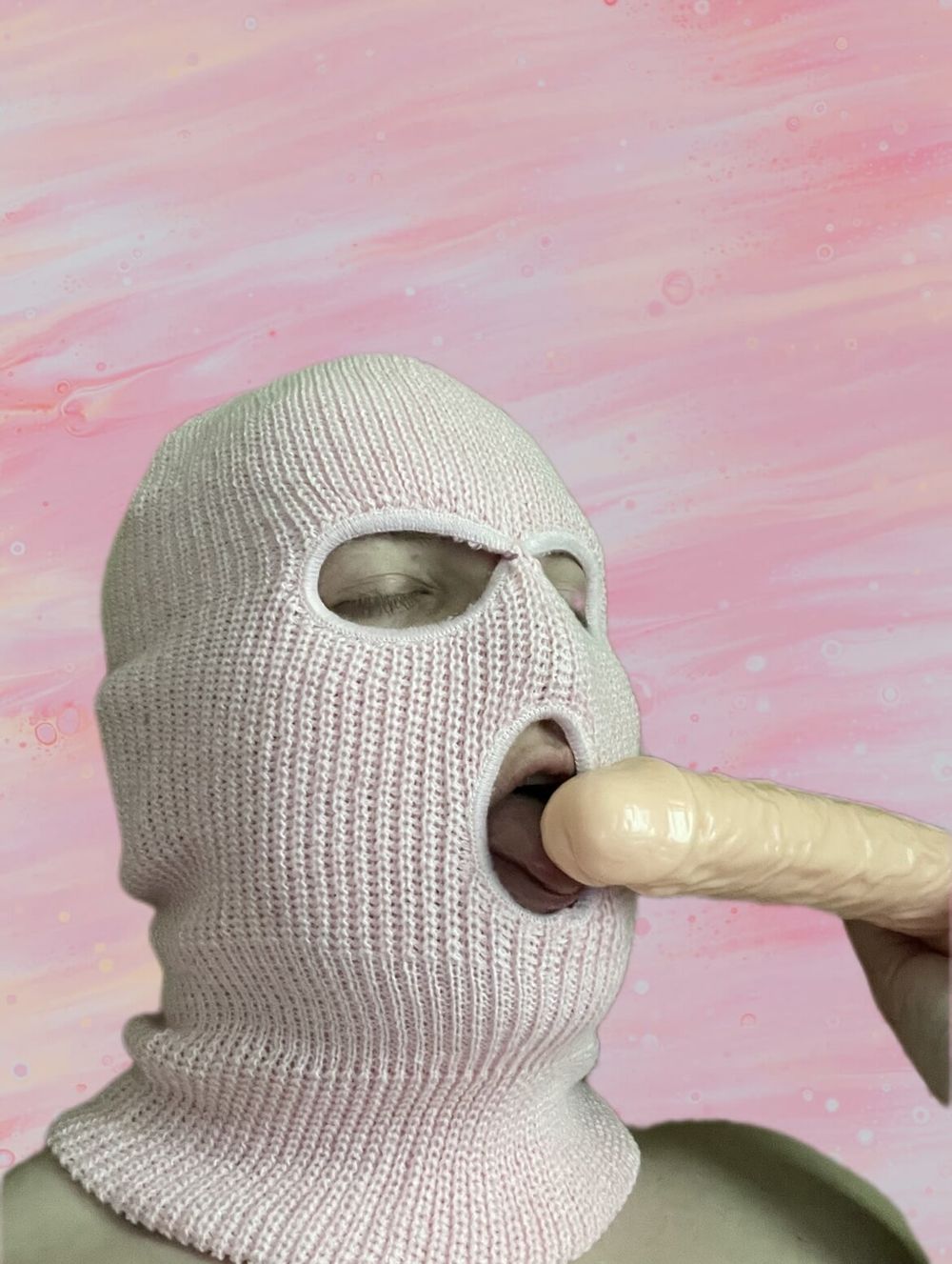 Playing with a dildo in a pink mask