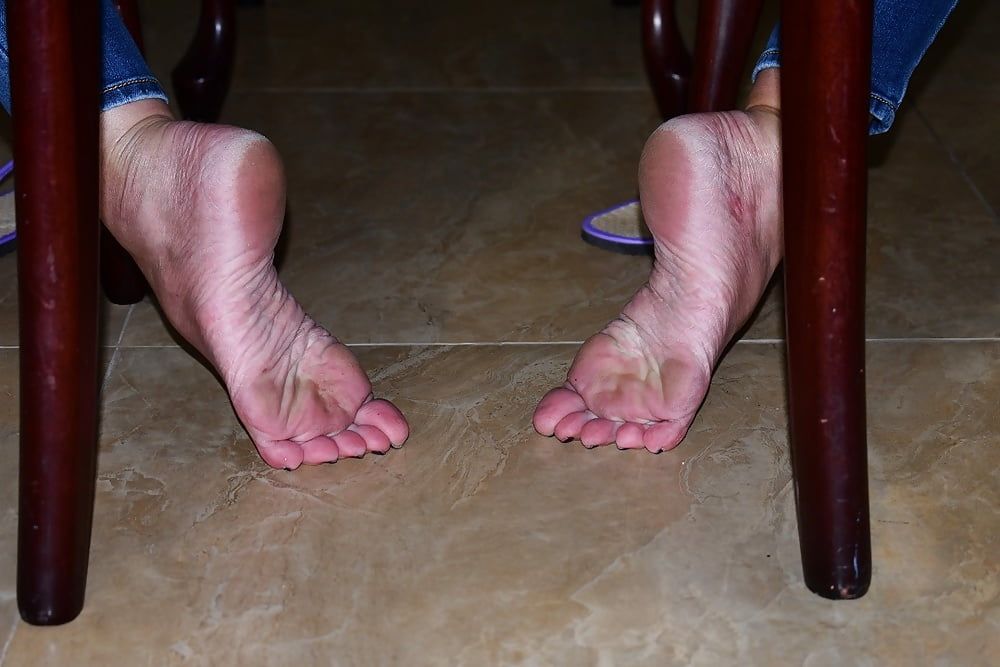 Dirty Bare Feet and Flip Flops Under the Chair